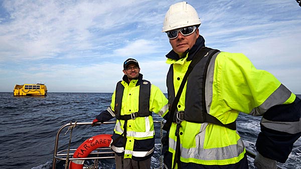 Deux ingénieurs GEPS Techno en mer lors d'une mission avec une bouée en arrière-plan